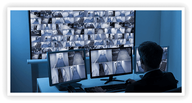 A man sitting in front of multiple computer monitors.