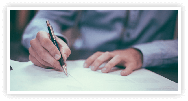 A person writing on paper with a pencil.