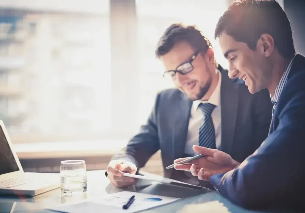 Two men in suits and ties looking at a tablet.