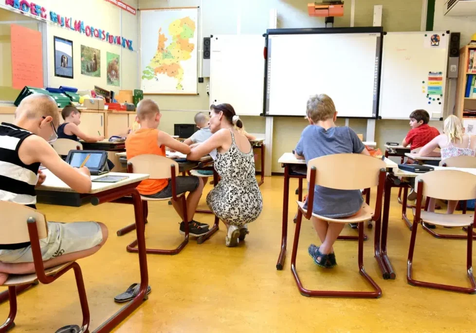 A group of people sitting at desks in front of a projector screen.